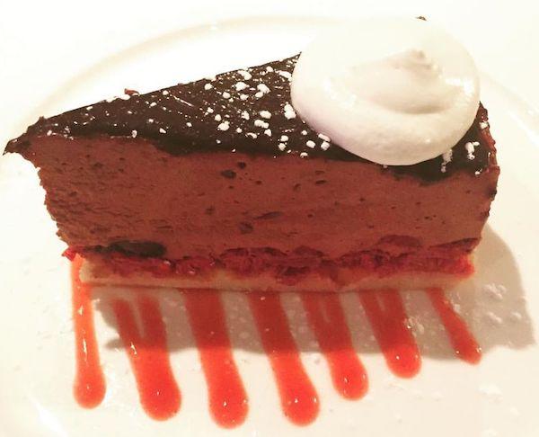 Chocolate mousse cake with whipped cream and raspberry sauce